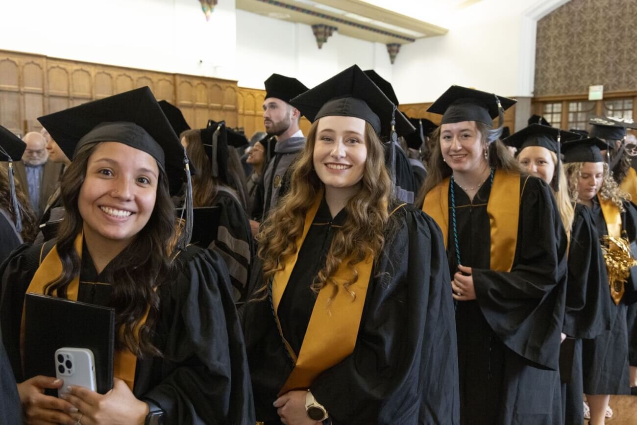 Veterinary school graduates smiling at the camera as they walk through the Purdue Memorial Union Ballroom